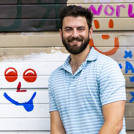 Micah Coltman - video producer at Lead Dog Digital Tyler TX sitting in front of a colorful wall.