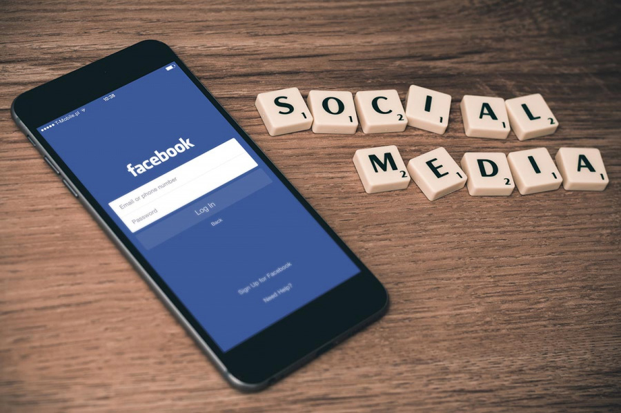 The phone with the Facebook opened is on the brown table. Next to it, with the wooden blocks, is written “social media”. It illustrates why it is important for your business to have a Facebook page.